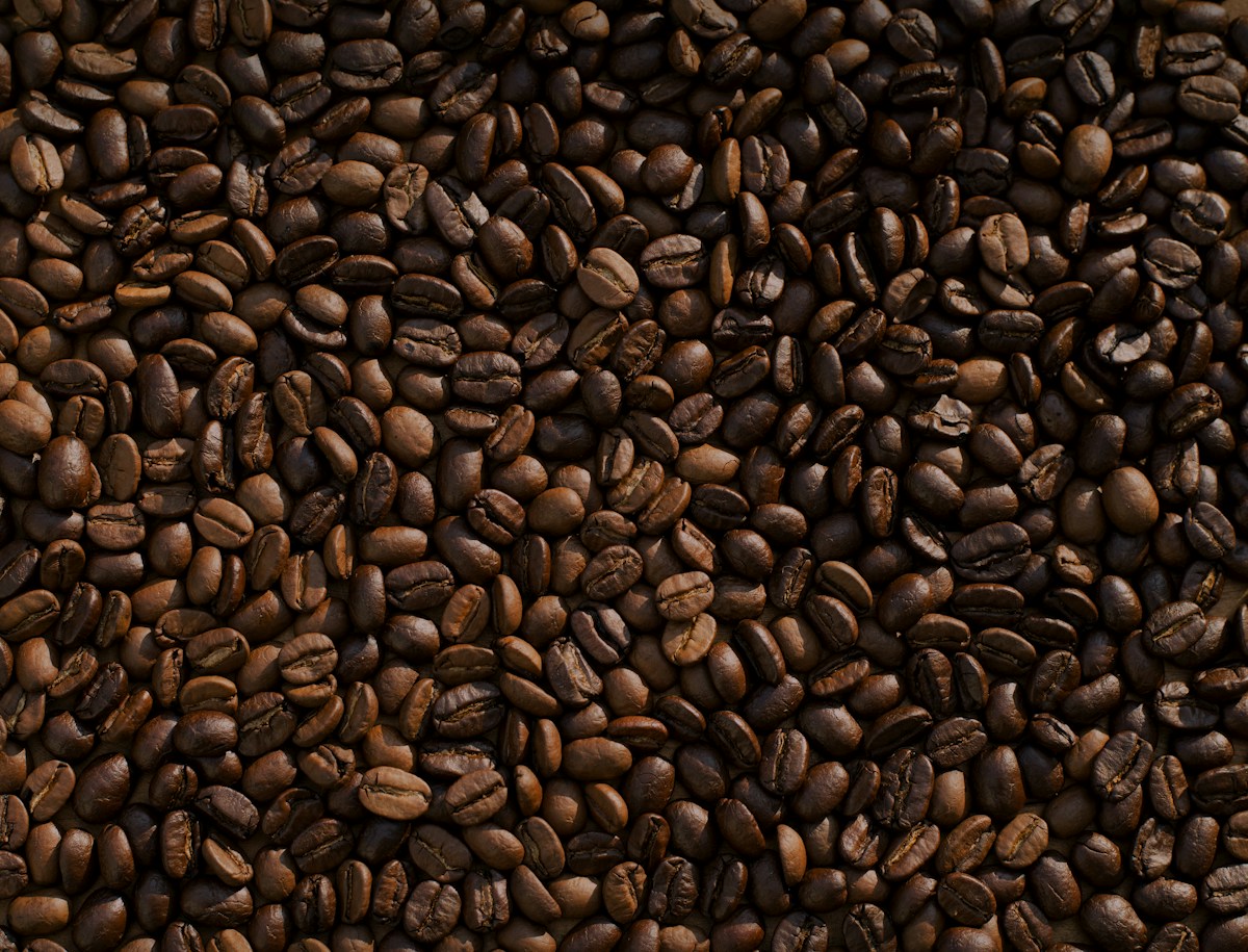 Coffee beans, brewing tools and cups laid out on a wooden table