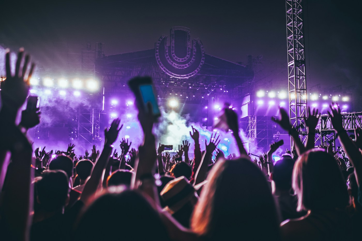 An energetic festival crowd reaching toward a live stage